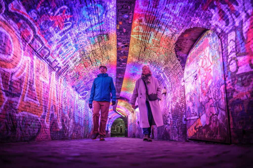 Twee mensen lopen door een verlichte tunnel in Utrecht - onderdeel van lichtkunstwerkenroute Utrecht Lumen